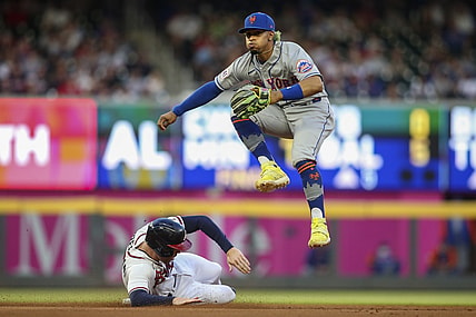 May 19, 2021; Atlanta, Georgia, USA; New York Mets shortstop Francisco Lindor (12) turns a double play over Atlanta Braves first baseman Freddie Freeman (5) in the fourth inning at Truist Park. Mandatory Credit: Brett Davis-USA TODAY Sports