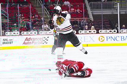 May 6, 2021; Raleigh, North Carolina, USA;  Carolina Hurricanes defenseman Jake Bean (24) dives to the ice to avoid the check by Chicago Blackhawks defenseman Nikita Zadorov (16) during the third period at PNC Arena. Mandatory Credit: James Guillory-USA TODAY Sports