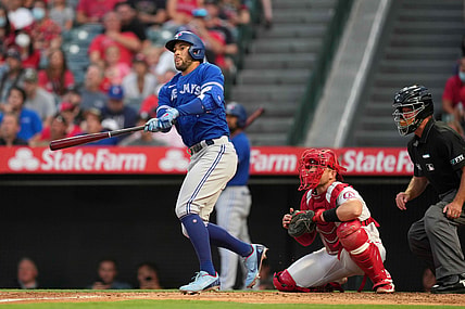 Aug 11, 2021; Anaheim, California, USA; Toronto Blue Jays center fielder George Springer (4) follows through on a solo home run in the second inning as Los Angeles Angels catcher Max Stassi (33) and umpire Ed Hickox (15) watch at Angel Stadium. Mandatory Credit: Kirby Lee-USA TODAY Sports
