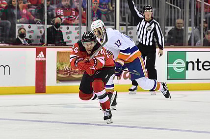 Nov 11, 2021; Newark, New Jersey, USA; New Jersey Devils defenseman Ty Smith (24) deflects the puck against New York Islanders left wing Matt Martin (17) during the second period at Prudential Center. Mandatory Credit: Catalina Fragoso-USA TODAY Sports