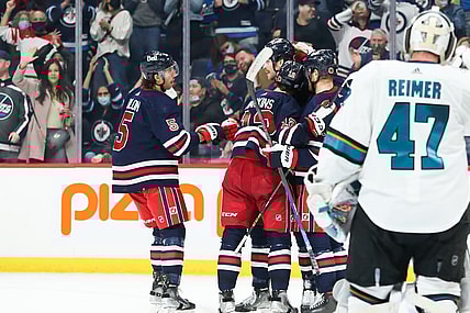 Nov 11, 2021; Winnipeg, Manitoba, CAN;  Winnipeg Jets forward Jansen Harkins (12) is congratulated by his teammates on his goal against the San Jose Sharks during the second period at Canada Life Centre. Mandatory Credit: Terrence Lee-USA TODAY Sports
