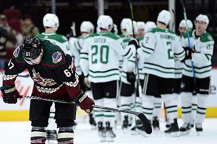 Nov 27, 2021; Glendale, Arizona, USA; Arizona Coyotes left wing Lawson Crouse (67) leaves the ice as Dallas Stars players celebrate their victory after the game at Gila River Arena. Mandatory Credit: Joe Camporeale-USA TODAY Sports