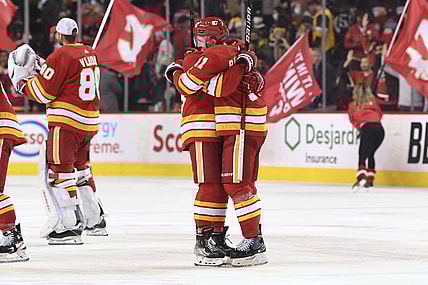 Nov 29, 2021; Calgary, Alberta, CAN; Calgary Flames defenseman Oliver Kylington (58) and forward Mikael Backlund (11) celebrate beating the Pittsburgh Penguins at Scotiabank Saddledome. Flames won 2-1 in a shootout. Mandatory Credit: Candice Ward-USA TODAY Sports
