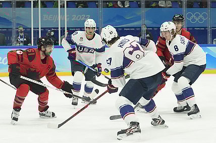 Feb 12, 2022; Beijing, China; Team Canada forward David Desharnais (51) fights for the puck with Team USA forward Matty Beniers (10), forward Matt Knies (67), and defender Jake Sanderson (8) during the first period in the men's ice hockey preliminary round of the Beijing 2022 Olympic Winter Games at National Indoor Stadium. Mandatory Credit: Rob Schumacher-USA TODAY Sports