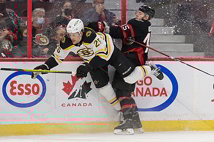 Feb 19, 2022; Ottawa, Ontario, CAN; Boston Bruins defenseman Brandon Carlo (25) is checked by Ottawa Senators left wing Parker Kelly (45) in the second period at the Canadian Tire Centre. Mandatory Credit: Marc DesRosiers-USA TODAY Sports