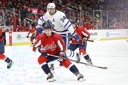 Feb 28, 2022; Washington, District of Columbia, USA; Toronto Maple Leafs center Auston Matthews (34) leaps around the check of Washington Capitals defenseman Dmitry Orlov (9) while chasing the puck in the second period at Capital One Arena. Mandatory Credit: Geoff Burke-USA TODAY Sports