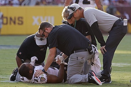 Aug 28, 2021; Landover, Maryland, USA; Baltimore Ravens head coach John Harbaugh (R) looks on as team medical personnel help Ravens running back J.K. Dobbins (27) after being injured against the Washington Football Team in the first quarter at FedExField. Mandatory Credit: Geoff Burke-USA TODAY Sports