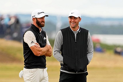 Jul 14, 2022; St. Andrews, SCT; Dustin Johnson (left) talks with Scottie Scheffler during a delay on the 14th hole during the first round of the 150th Open Championship golf tournament at St. Andrews Old Course. Mandatory Credit: Rob Schumacher-USA TODAY Sports