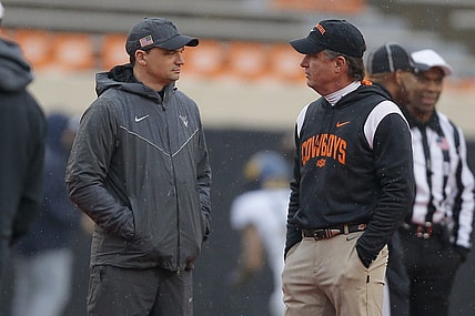 Nov 26, 2022; Stillwater, Oklahoma, USA; West Virginia Mountaineers head coach Neal Brown, left, and Oklahoma State Cowboys head coach Mike Gundy talk before a college football game between Oklahoma State and West Virginia at Boone Pickens Stadium in Stillwater, Okla., Saturday, Nov. 26, 2022.   Mandatory Credit: Bryan Terry-USA TODAY Sports