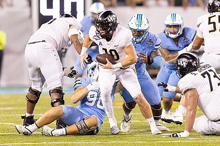 Dec 3, 2022; New Orleans, Louisiana, USA; UCF Knights quarterback John Rhys Plumlee (10) scrambles away from Tulane Green Wave defensive lineman Patrick Jenkins (0) during the second half at Yulman Stadium. Mandatory Credit: Stephen Lew-USA TODAY Sports