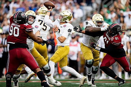 Dec 30, 2022; Jacksonville, FL, USA; Notre Dame Fighting Irish quarterback Tyler Buchner (12) throws the ball under pressure from South Carolina Gamecocks defensive lineman Tonka Hemingway (91) and defensive lineman T.J. Sanders (90) during the first half in the 2022 Gator Bowl at TIAA Bank Field. Mandatory Credit: Matt Pendleton-USA TODAY Sports
