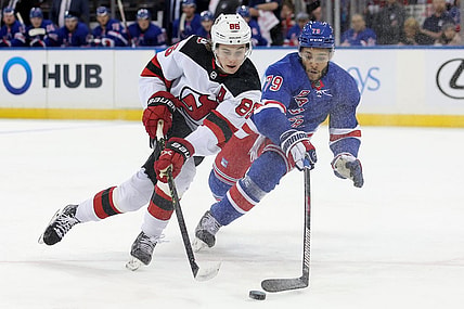 Dec 12, 2022; New York, New York, USA; New York Rangers defenseman K'Andre Miller (79) knocks the puck away from New Jersey Devils center Jack Hughes (86) during the first period at Madison Square Garden. Mandatory Credit: Brad Penner-USA TODAY Sports