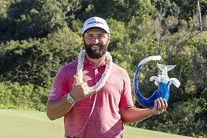 January 8, 2023; Maui, Hawaii, USA; Jon Rahm hoists the trophy on the 18th hole during the final round of the Sentry Tournament of Champions golf tournament at Kapalua Resort - The Plantation Course. Mandatory Credit: Kyle Terada-USA TODAY Sports