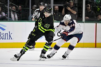 Feb 18, 2023; Dallas, Texas, USA; Dallas Stars left wing Jason Robertson (21) keeps the puck away from Columbus Blue Jackets right wing Mathieu Olivier (24) during the first period at the American Airlines Center. Mandatory Credit: Jerome Miron-USA TODAY Sports