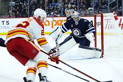 Apr 5, 2023; Winnipeg, Manitoba, CAN;  Winnipeg Jets goalie Connor Hellebuyck (37) watches Calgary Flames forward Trevor Lewis (22) during the first period at Canada Life Centre. Mandatory Credit: Terrence Lee-USA TODAY Sports
