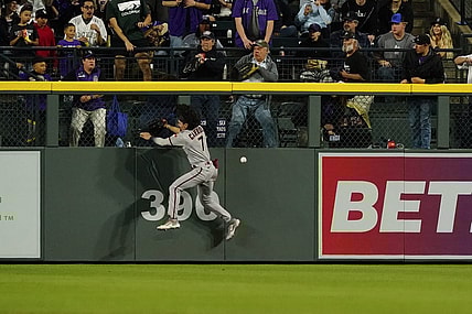 Apr 29, 2023; Denver, Colorado, USA;  Arizona Diamondbacks left fielder Corbin Carroll (7) falls after banging into the outfield wall at Coors Field.  Carroll left the game after the play. Mandatory Credit: Michael Madrid-USA TODAY Sports