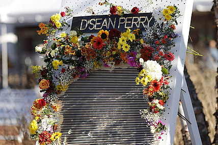 Nov 19, 2022; Charlottesville, Virginia, US; A partial view of a flower board with an image of D'Sean Perry, one of three Virginia Cavaliers football players killed in a campus shooting on November 13th is displayed prior to the start of a memorial at John Paul Jones Arena. Mandatory Credit: Geoff Burke-USA TODAY Sports