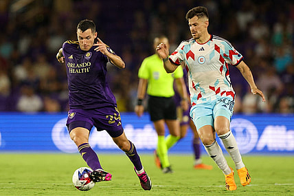 Jul 1, 2023; Orlando, Florida, USA;  Orlando City SC defender Kyle Smith (24) controls the ball from Chicago Fire FC midfielder Gaston Gimenez (30) in the second half at Exploria Stadium. Mandatory Credit: Nathan Ray Seebeck-USA TODAY Sports
