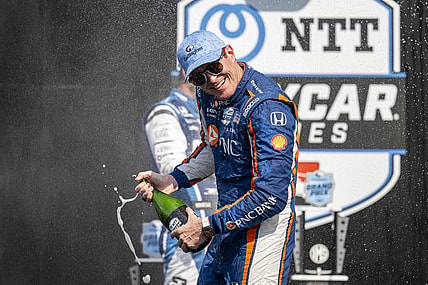 Aug 12, 2023; Speedway, Indiana, USA; Chip Ganassi Racing driver Scott Dixon (9) turns away from Rahal Letterman Lanigan Racing driver Graham Rahal (15) during the champagne fight on the podium after the Gallagher Grand Prix at the Indianapolis Motor Speedway Road Course. Mandatory Credit: Marc Lebryk-USA TODAY Sports