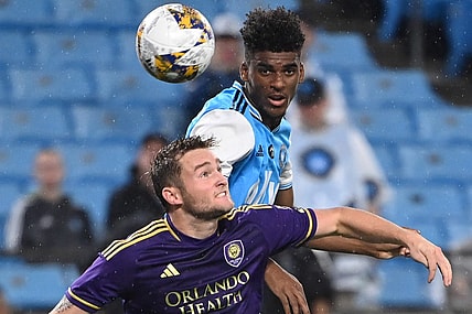 Aug 30, 2023; Charlotte, North Carolina, USA; Charlotte FC defender Adilson Malanda (29) heads the ball as Orlando City forward Duncan McGuire (13) defends in the first half at Bank of America Stadium. Mandatory Credit: Bob Donnan-USA TODAY Sports
