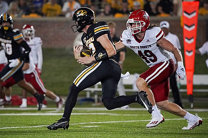 Aug 31, 2023; Columbia, Missouri, USA; Missouri Tigers quarterback Brady Cook (12) runs the ball as South Dakota Coyotes linebacker Brock Mogensen (49) defends during the first half at Faurot Field at Memorial Stadium. Mandatory Credit: Denny Medley-USA TODAY Sports