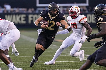 Sep 1, 2022; Winston-Salem, North Carolina, USA; Wake Forest Demon Deacons quarterback Mitch Griffis (12) runs past Virginia Military Institute Keydets linebacker Jason Johnson (18) during the first half at Truist Field. Mandatory Credit: Jim Dedmon-USA TODAY Sports