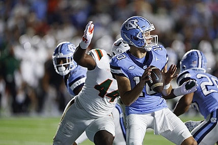 Oct 14, 2023; Chapel Hill, North Carolina, USA; North Carolina Tar Heels quarterback Drake Maye (10) looks to pass as he is chased by Miami Hurricanes defensive lineman Rueben Bain Jr. (44) in the first half at Kenan Memorial Stadium. Mandatory Credit: Nell Redmond-USA TODAY Sports