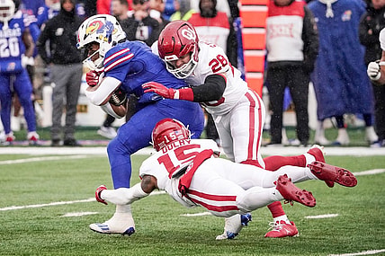 Oct 28, 2023; Lawrence, Kansas, USA; Kansas Jayhawks running back Devin Neal (4) runs the ball as Oklahoma Sooners linebacker Danny Stutsman (28) and defensive back Kendel Dolby (15) make the tackle during the first half at David Booth Kansas Memorial Stadium. Mandatory Credit: Denny Medley-USA TODAY Sports
