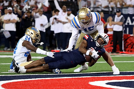 Nov 4, 2023; Tucson, Arizona, USA; Arizona Wildcats wide receiver Montana Lemonious-Craig #5 dives into the endzone against UCLA Bruins defensive back Jaylin Davies #24 and defensive lineman Laiatu Latu #15  during the first half at Arizona Stadium. Mandatory Credit: Zachary BonDurant-USA TODAY Sports