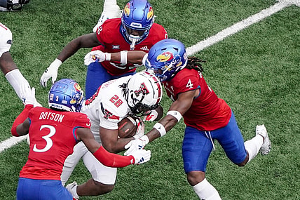 Nov 11, 2023; Lawrence, Kansas, USA; Kansas Jayhawks cornerback Mello Dotson (3) and safety Marvin Grant (4) tackle Texas Tech Red Raiders running back Tahj Brooks (28) during the first half at David Booth Kansas Memorial Stadium. Mandatory Credit: Denny Medley-USA TODAY Sports