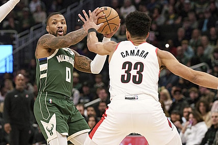 Nov 26, 2023; Milwaukee, Wisconsin, USA;  Milwaukee Bucks guard Damian Lillard (0) looks to pass the ball under pressure from Portland Trail Blazers forward Toumani Camara (33) during the first quarter at Fiserv Forum. Mandatory Credit: Jeff Hanisch-USA TODAY Sports