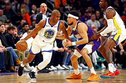 Dec 12, 2023; Phoenix, Arizona, USA; Golden State Warriors guard Chris Paul (3) drives to the basket against Phoenix Suns guard Devin Booker (1) during the first quarter at Footprint Center. Mandatory Credit: Mark J. Rebilas-USA TODAY Sports