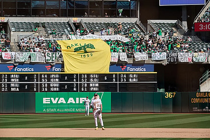 Sep 24, 2023; Oakland, California, USA; Fans in the outfield bleachers display homemade signs critical of the MLB Commissioner and Oakland Athletics ownership and Oakland Athletics infielder Zack Gelof (20) and outfielder Brent Rooker (25) stand on the field during the eighth inning against the Detroit Tigers at Oakland-Alameda County Coliseum. Mandatory Credit: Robert Edwards-USA TODAY Sports