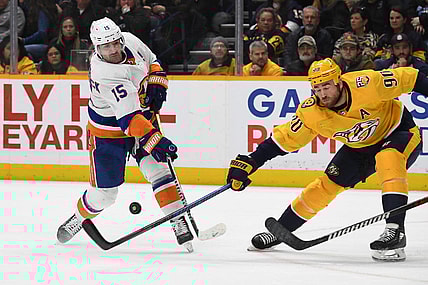 Jan 13, 2024; Nashville, Tennessee, USA; New York Islanders right wing Cal Clutterbuck (15) shoots the puck against Nashville Predators center Ryan O'Reilly (90) during the second period at Bridgestone Arena. Mandatory Credit: Christopher Hanewinckel-USA TODAY Sports