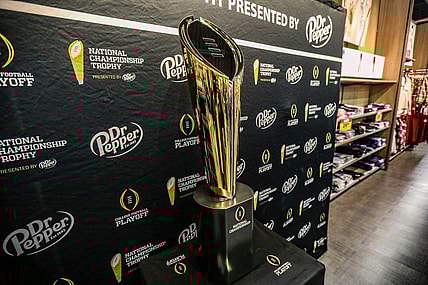 Fans stop to take photos with the College Football National Championship trophy at Meijer in Ypsilanti, Mich. on Thursday, Jan. 11, 2024. The trophy is going on a tour for fans to see presented by Dr. Pepper.