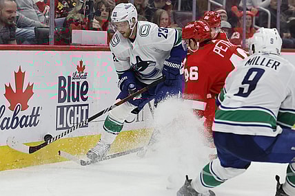 Feb 10, 2024; Detroit, Michigan, USA;  Vancouver Canucks center Elias Lindholm (23) skates with the puck defended by Detroit Red Wings defenseman Jeff Petry (46) in the third period at Little Caesars Arena. Mandatory Credit: Rick Osentoski-USA TODAY Sports