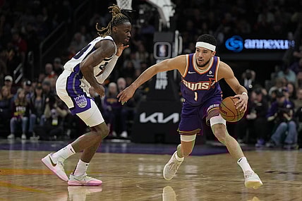 Feb 13, 2024; Phoenix, Arizona, USA; Phoenix Suns guard Devin Booker (1) drives on Sacramento Kings guard Keon Ellis (23) in the first half at Footprint Center. Mandatory Credit: Rick Scuteri-USA TODAY Sports