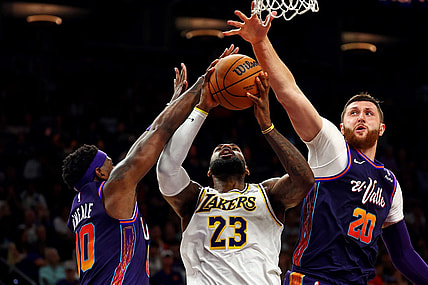 Feb 25, 2024; Phoenix, Arizona, USA; Los Angeles Lakers forward LeBron James (23) shoots the ball against Phoenix Suns forward Royce O'Neale (00) and center Jusuf Nurkic (20) during the fourth quarter at Footprint Center. Mandatory Credit: Mark J. Rebilas-USA TODAY Sports
