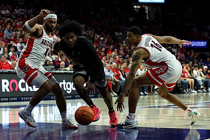 Feb 24, 2024; Tucson, Arizona, USA; Washington Huskies guard Sahvir Wheeler (5) drives to the net against Arizona Wildcats guard Kylan Boswell (4) and forward Keshad Johnson (16) during the first half at McKale Center. Mandatory Credit: Zachary BonDurant-USA TODAY Sports