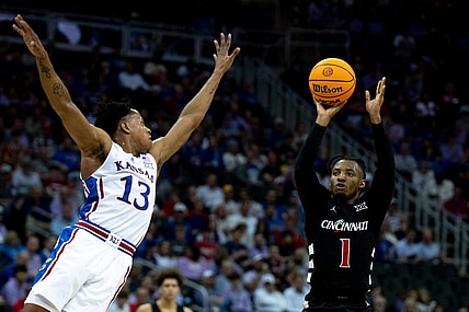 Cincinnati Bearcats guard Day Day Thomas (1) hits a 3-point basket as Kansas Jayhawks guard Elmarko Jackson (13) defends in the first half of the Big 12 Conference tournament game between Cincinnati Bearcats and Kansas Jayhawks at T-Mobile Center in Kansas City, Mo., on Wednesday, March 13, 2024.