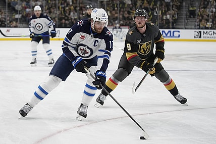 Winnipeg Jets center Adam Lowry (17) skates up the ice against Vegas Golden Knights center Jack Eichel (9) during the first period of an NHL hockey game Thursday, April 3, 2025, in Las Vegas. (AP Photo/John Locher)