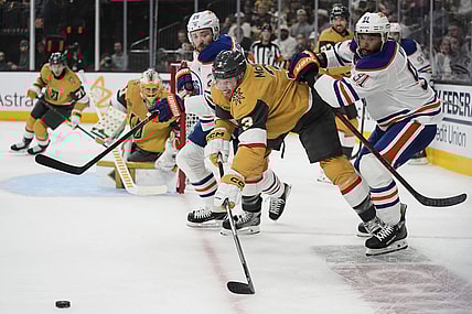 From right, Edmonton Oilers left wing Evander Kane (91), Vegas Golden Knights defenseman Brayden McNabb (3) and Edmonton Oilers center Leon Draisaitl (29) vie for the puck during the first period of Game 1 of a second-round NHL hockey playoff series Tuesday, May 6, 2025, in Las Vegas. (AP Photo/John Locher)