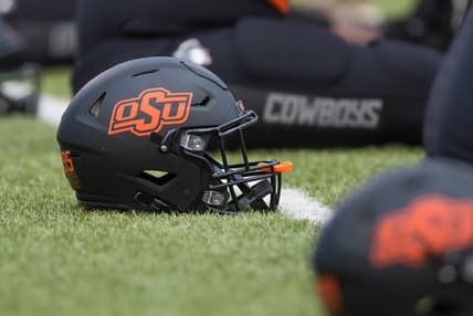 Oct 31, 2020; Stillwater, Oklahoma, USA;  Oklahoma State Cowboys helmets lie on the field as players stretch before a game against the Texas Longhorns at Boone Pickens Stadium. Mandatory Credit: Brett Rojo-USA TODAY Sports