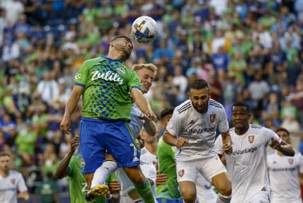Aug 14, 2022; Seattle, Washington, USA; Seattle Sounders FC midfielder Cristian Roldan (7) jumps to head a corner kick against Real Salt Lake defender Jasper Loffelsend (28) and forward Justin Meram (right) during the first half at Lumen Field. Mandatory Credit: Joe Nicholson-USA TODAY Sports