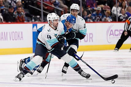 Nov 9, 2023; Denver, Colorado, USA; Seattle Kraken defenseman Justin Schultz (4) controls the puck under pressure from Colorado Avalanche right wing Mikko Rantanen (96) as center Alex Wennberg (21) looks on in the second period at Ball Arena. Mandatory Credit: Isaiah J. Downing-USA TODAY Sports