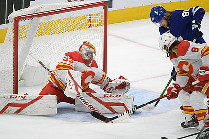 Feb 22, 2021; Toronto, Ontario, CAN;   Calgary Flames goalie David Rittich (33) makes a save as defenseman Christopher Tanev (8) battles with Toronto Maple Leafs forward William Nylander (88) in the first period at Scotiabank Arena. Mandatory Credit: Dan Hamilton-USA TODAY Sports