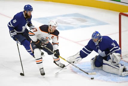 Jan 20, 2021; Toronto, Ontario, CAN; Edmonton Oilers forward Connor McDavid (97) cuts between Toronto Maple Leafs goalie Frederik Andersen (31) and defenseman Jake Muzzin (8) in the first period at Scotiabank Arena. Mandatory Credit: Dan Hamilton-USA TODAY Sports