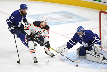 Jan 20, 2021; Toronto, Ontario, CAN; Edmonton Oilers forward Connor McDavid (97) cuts between Toronto Maple Leafs goalie Frederik Andersen (31) and defenseman Jake Muzzin (8) in the first period at Scotiabank Arena. Mandatory Credit: Dan Hamilton-USA TODAY Sports
