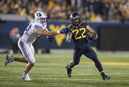 Nov 4, 2023; Morgantown, West Virginia, USA; West Virginia Mountaineers running back Jahiem White (22) runs the ball and avoids a tackle from Brigham Young Cougars defensive end Blake Mangelson (93) during the second quarter at Mountaineer Field at Milan Puskar Stadium. Mandatory Credit: Ben Queen-USA TODAY Sports