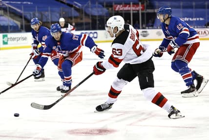 Feb 16, 2021; New York, New York, USA;  Jesper Bratt #63 of the New Jersey Devils takes a shot as Kevin Rooney #17 and Julien Gauthier #12 of the New York Rangers defend during the first period at Madison Square Garden. Mandatory Credit:  Elsa/POOL PHOTOS-USA TODAY Sports